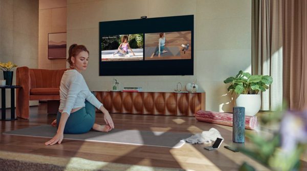 Samsung Q80A on wall with woman using for yoga class